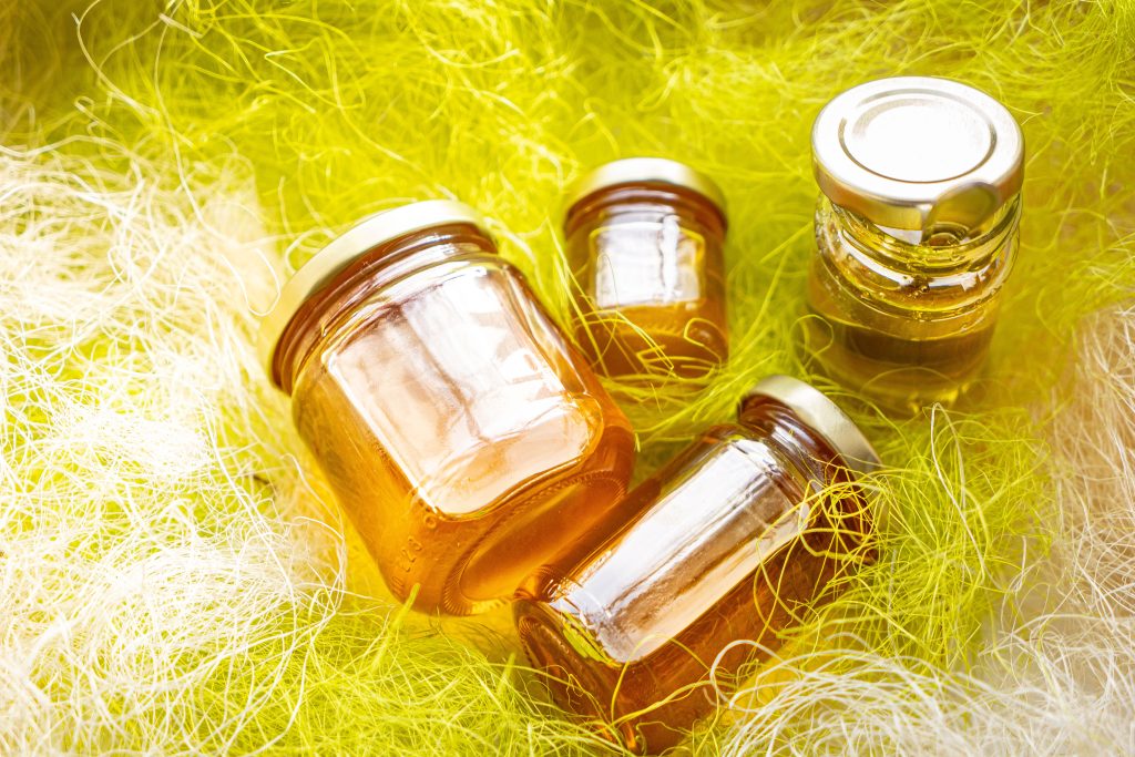 Natural honey in various jars on a wooden shelf, souvenir village market.